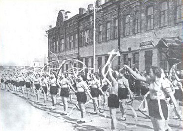 Учащиеся медицинского училища занимаются спортом на фоне зданий Краеведческого музея (пер. Достоевского, 34), которые до революции в начале ХХ века принадлежали известным и уважаемым сызранским купцам Н. А. Леднёву и А. Ф. Митюрину